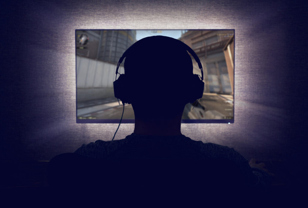 person in gaming headphones looking at a screen, playing a video game. 