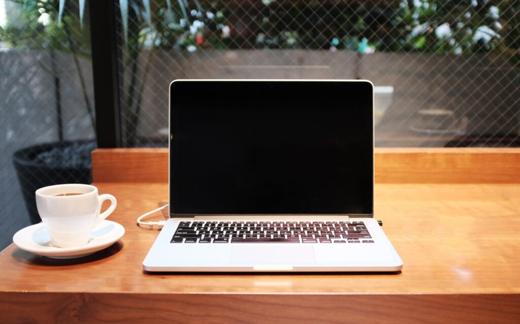 laptop sitting on table with coffee cup next to it 