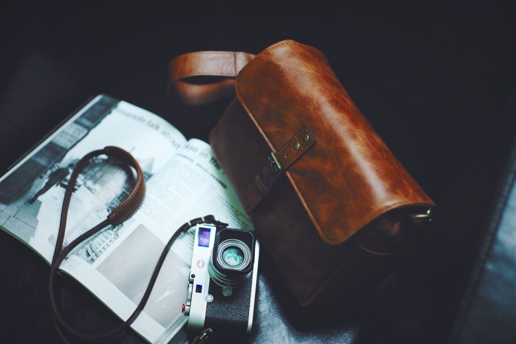 a brown leather bag and a leica camera on a newspaper