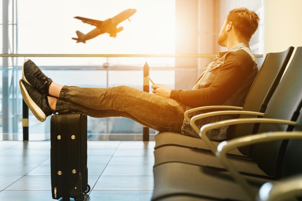 a man in an airport terminal with an airplane taking off in the background