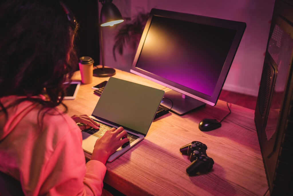girl sitting at desk with laptop and gaming controller