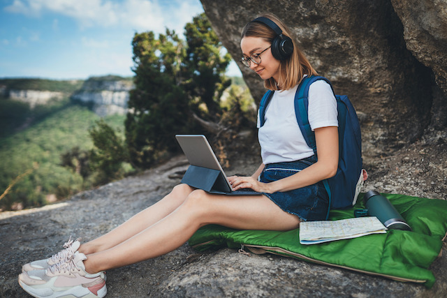 women sitting with laptop under a tree