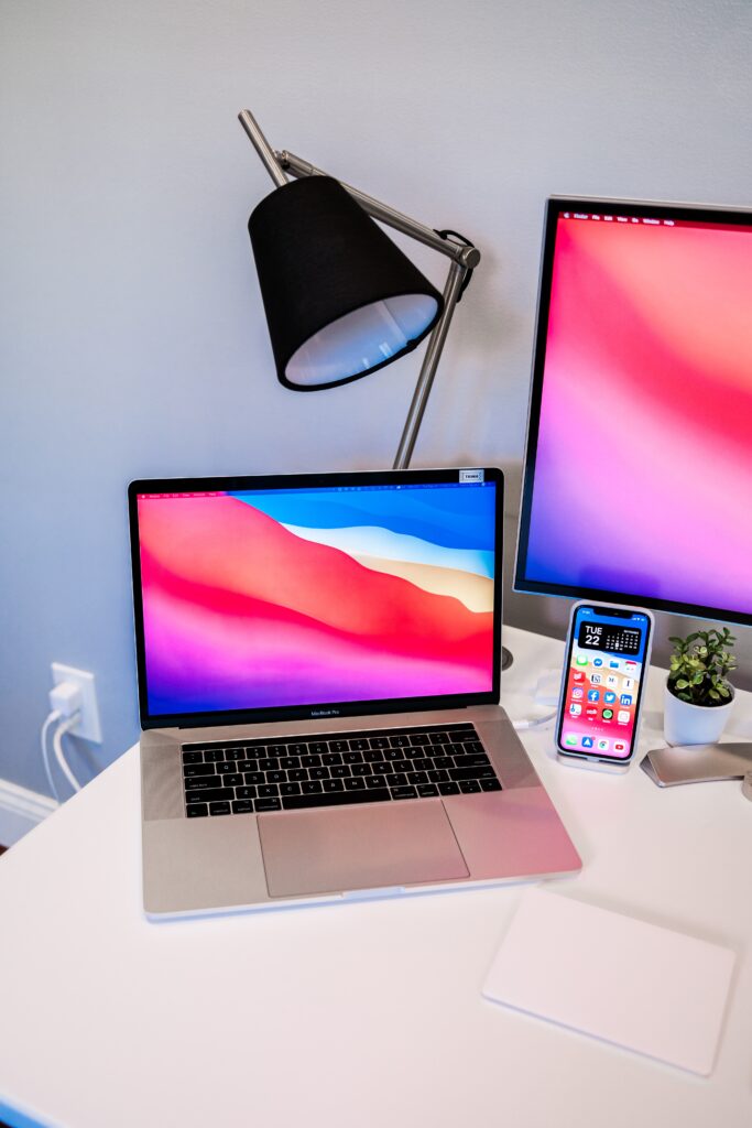 Monitor, laptop, and phone sitting on desk, all with matching vibrant screen background
