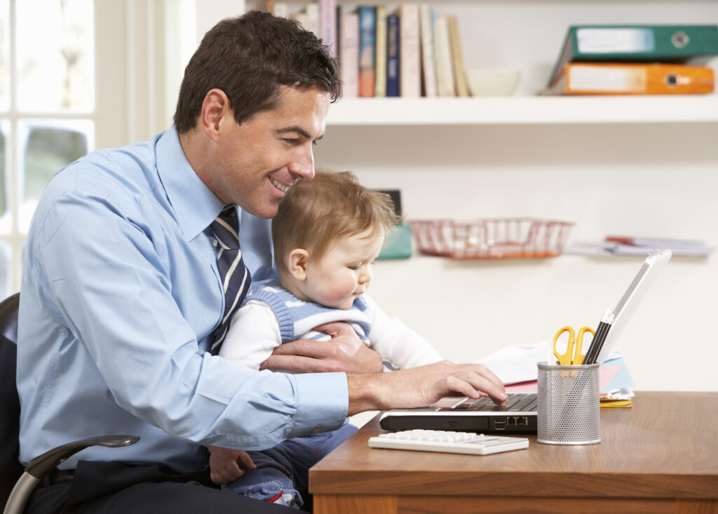 man with baby on his lap working on a laptop from home