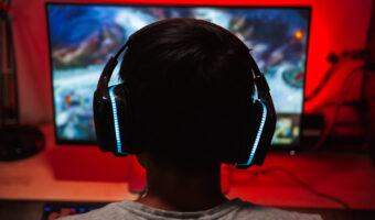 Guy with headphones on playing game on PC set up