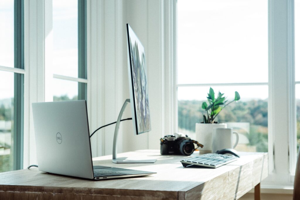 Laptop sitting on desk next to monitor and other office supplies