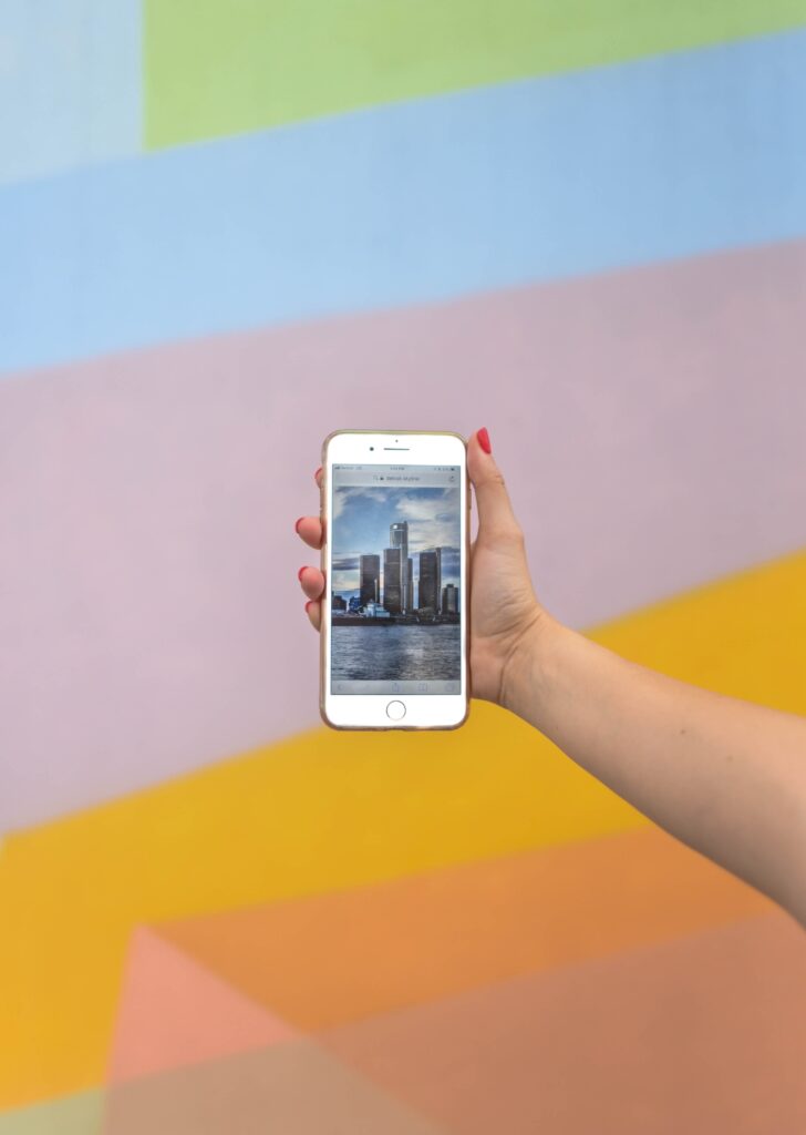 person holding white iphone against colorful background