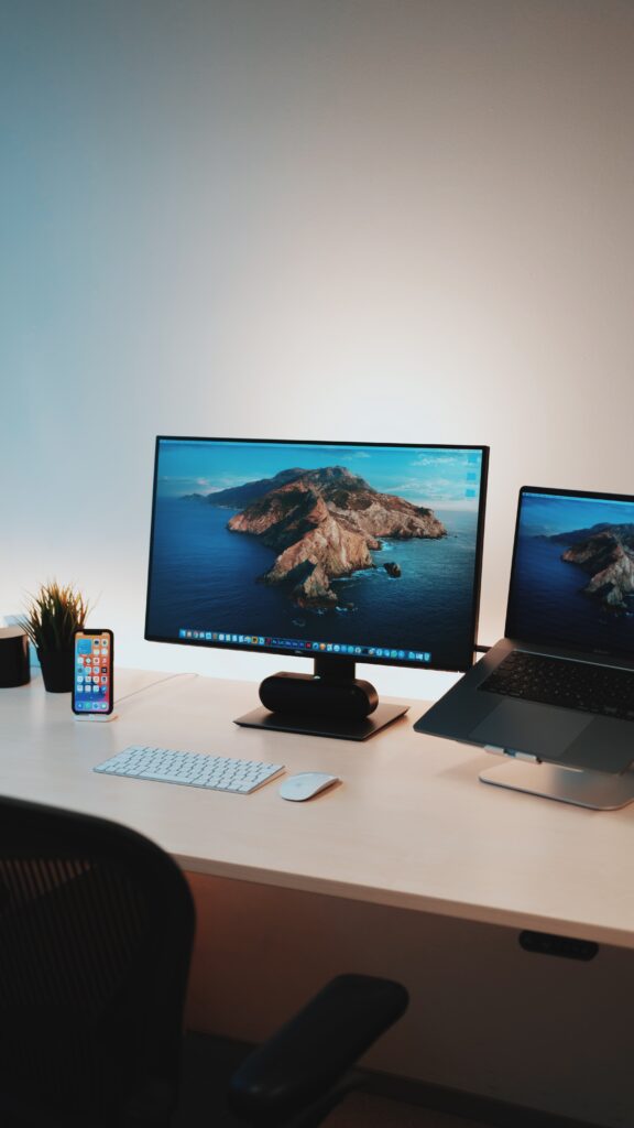 monitor sitting on desk with iphone and laptop