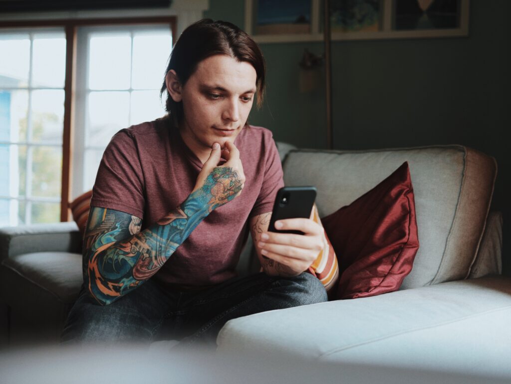 man in tattoos looking at his iphone