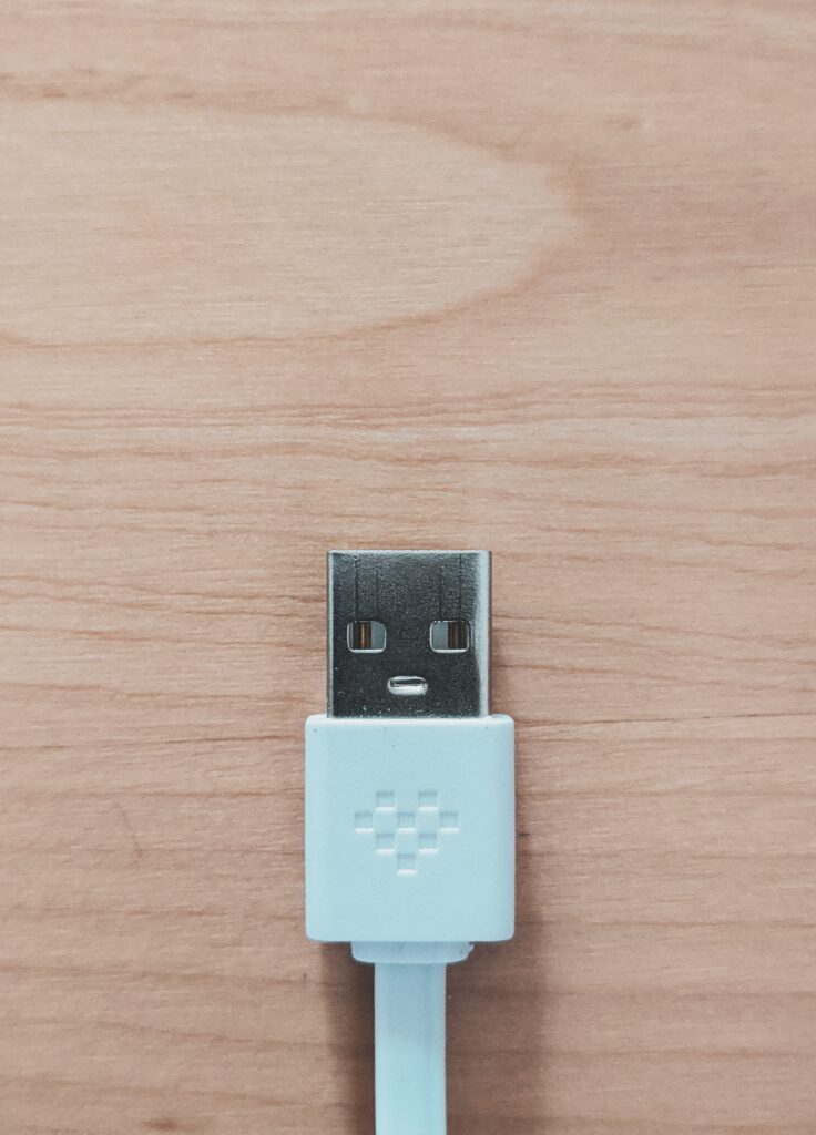 blue USB cable sitting on natural wood desk