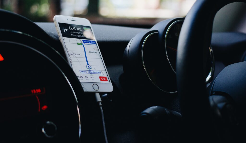 iphone with apple maps display on screen, plugged into a car charger