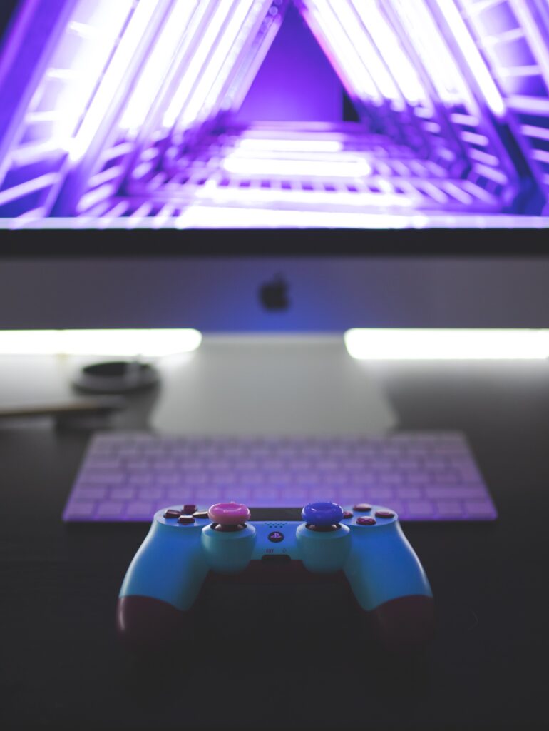 blue gaming controller sitting on a desk in front of screen