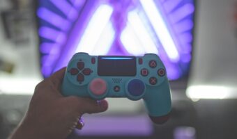 person holding a blue gaming controller in front of screen