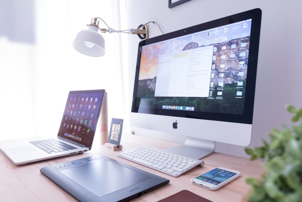 iMac sitting on desk with iphone, ipad, and laptop sitting on desk next to it