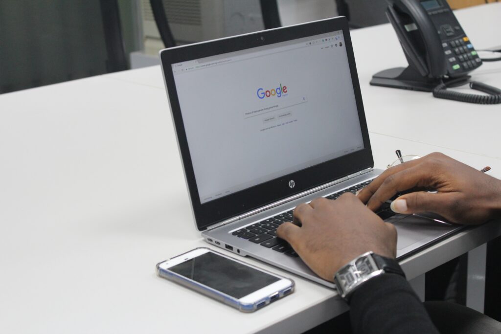 person typing on computer with phone sitting next to them