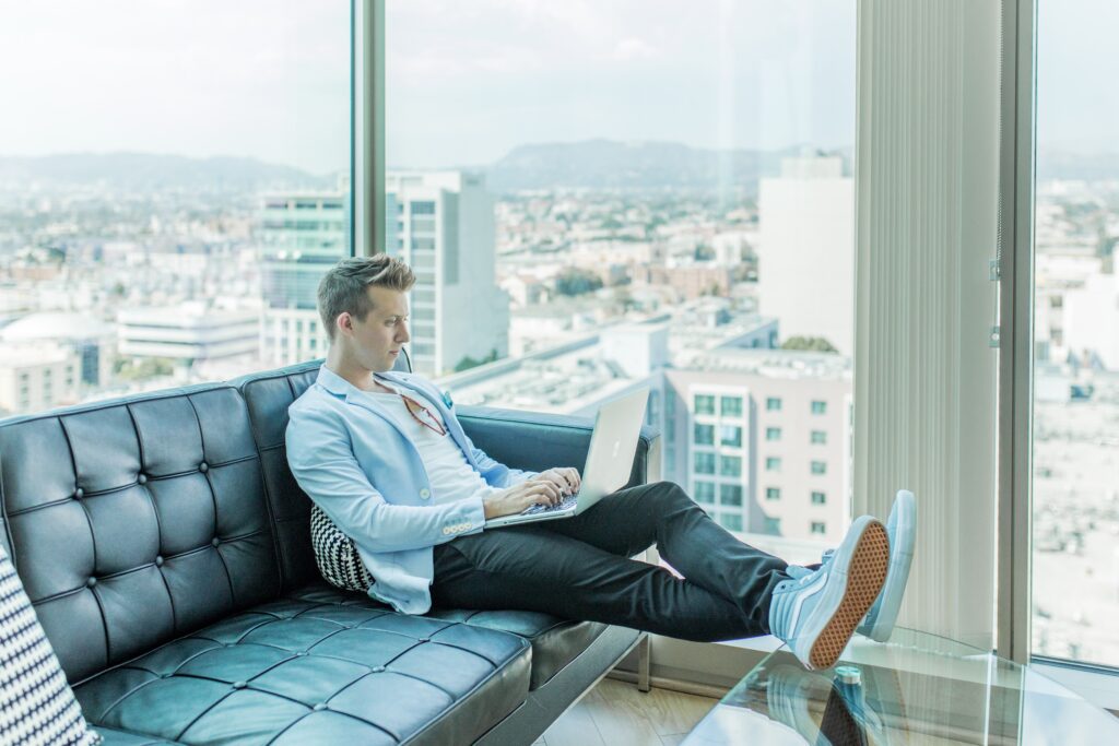 man sitting on couch working on his laptop