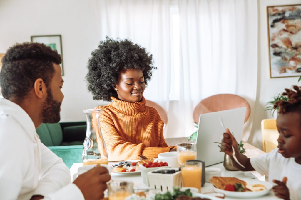 Wife working at the table while husband and child eat breakfast