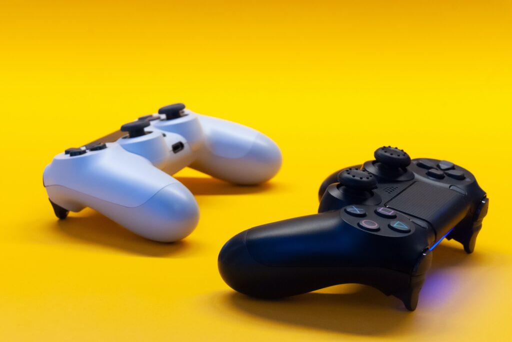 Two gaming controllers facing each other on a yellow background