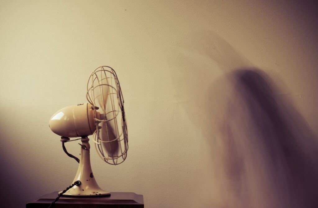 A moody scene of a small fan casting a shadow