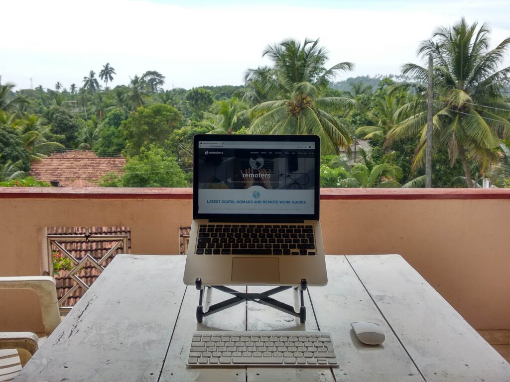 Laptop set up on workstation overlooking tropical tree tops