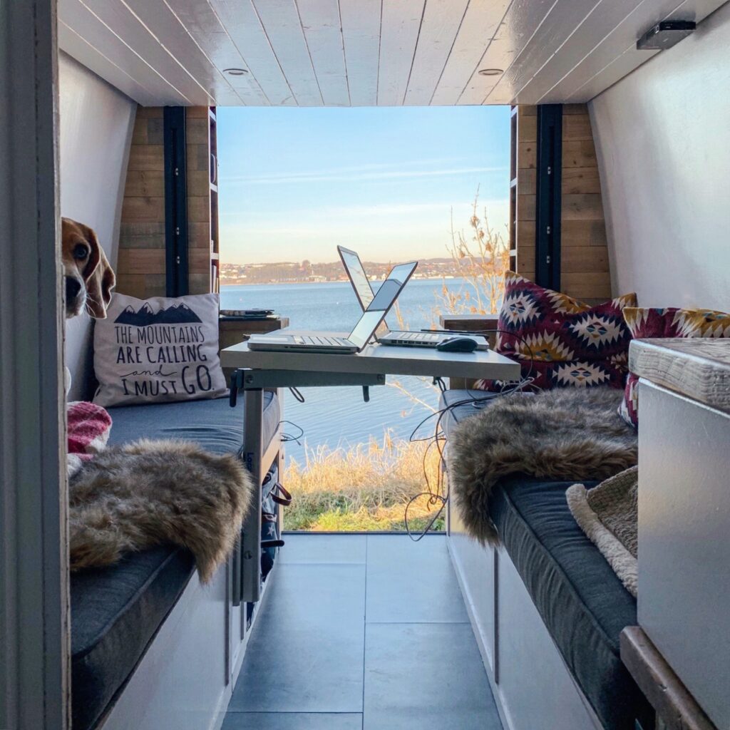 View of remote work setup inside a camper van overlooking a lake